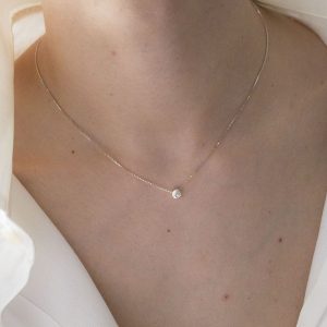Gargantilla con colgante de plata 925 de 5mm de diámetro, y circonita talla brillante de 2mm. Cadena de plata 925, longitud opcional 40, 45 o 50cm. Cierre de "reasa" pequeña. Objeto diseñado y fabricado artesanalmente en Madrid, España, por el estudio-taller de malicia. Este anillo ha sido fabricado por personas que disfrutan su trabajo.